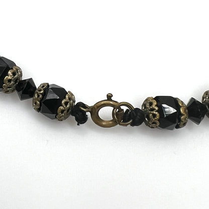 Brass-tone spring ring clasp detail on vintage jet black glass bead necklace