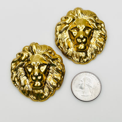 Gold tone lion head earrings beside quarter for scale