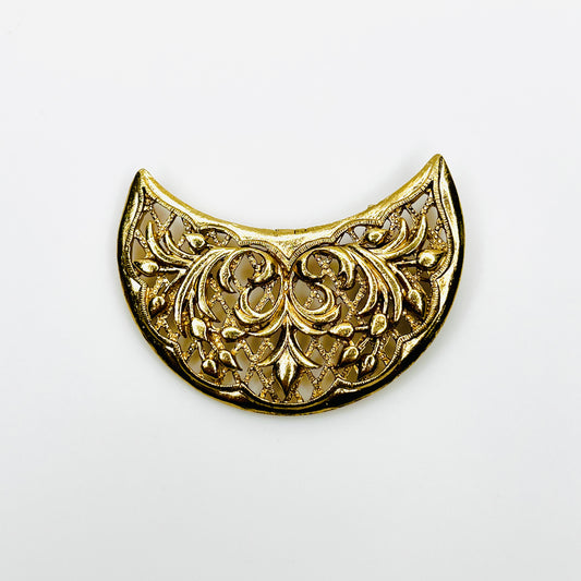 Vintage 1960s Lisner gold-tone horned crescent brooch featuring ornate floral scrollwork, raised buds, and intricate openwork filigree.