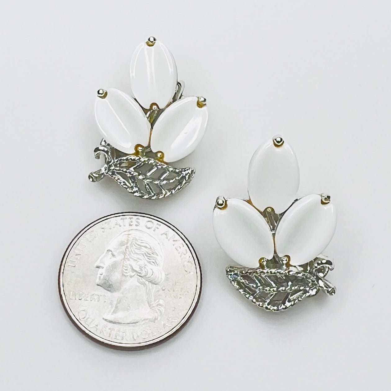 Signed Lisner white thermoset clip-on earrings shown beside quarter for scale