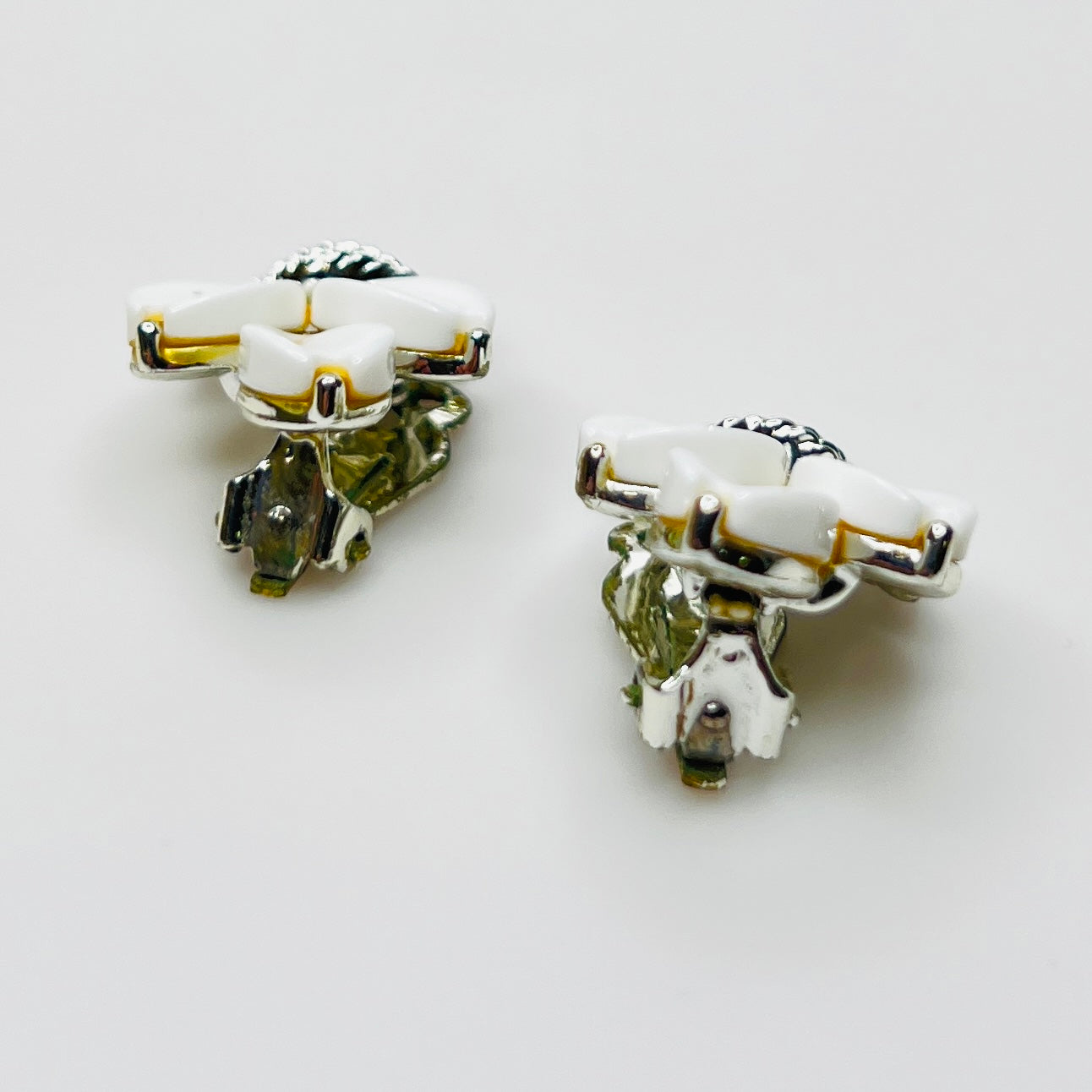 Side view of vintage Lisner white lucite clip-on earrings in silver-tone setting