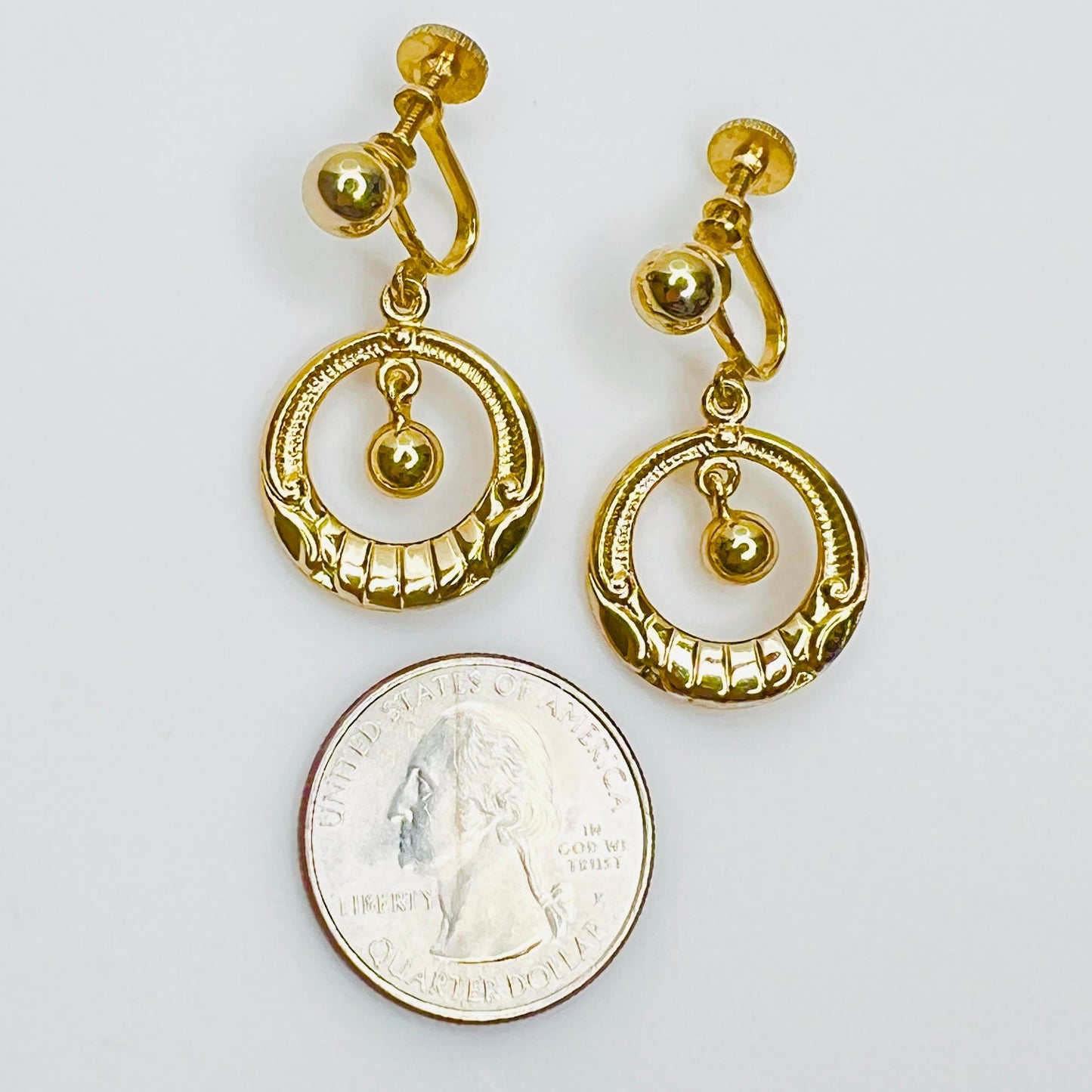 Mid Century gold tone dangle earrings beside quarter