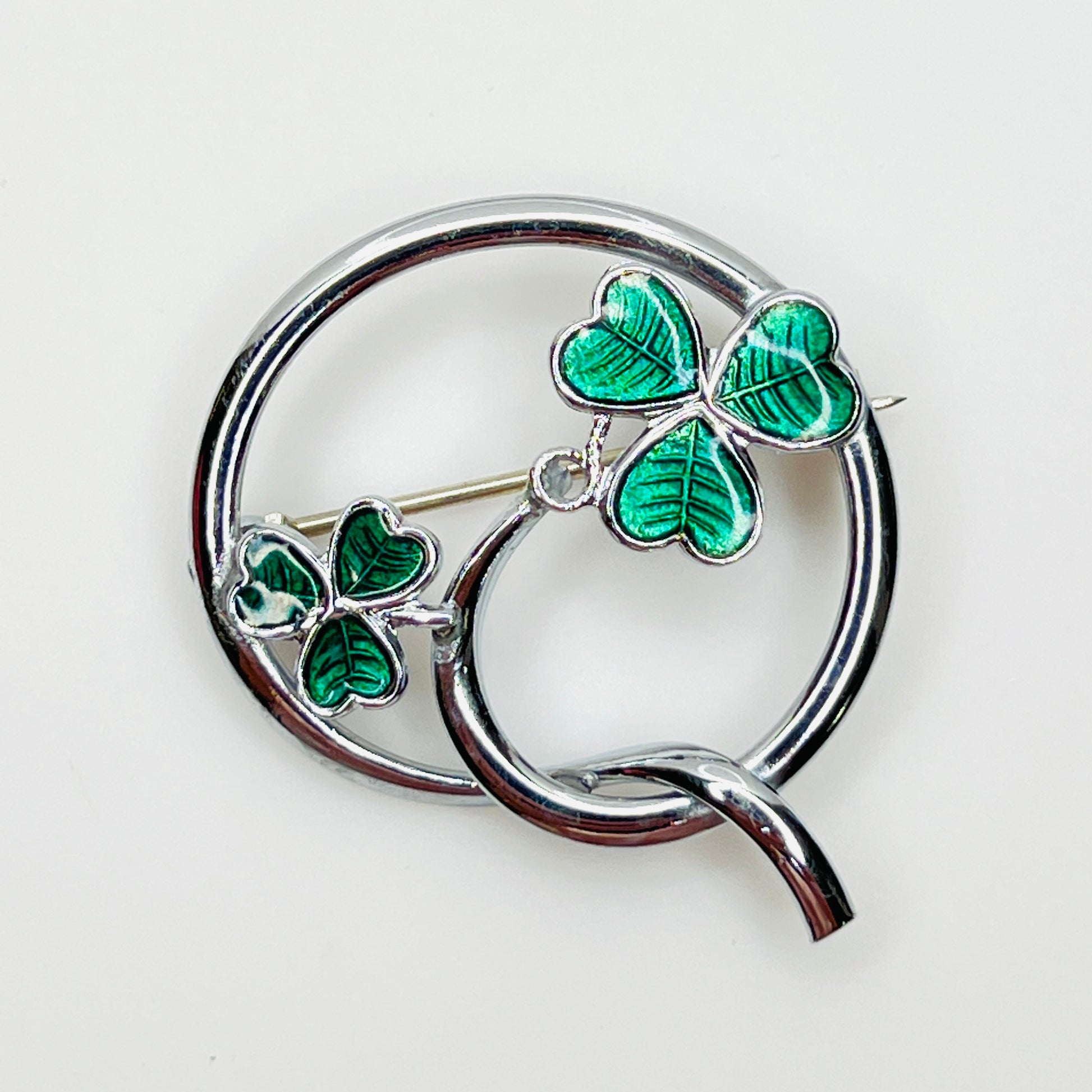 Vintage Mizpah green enamel double shamrock brooch with silver-tone circular design.