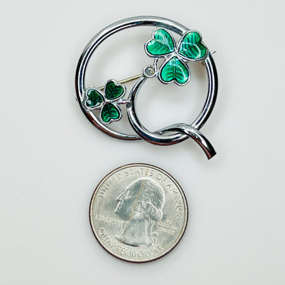 Signed Mizpah enamel shamrock brooch beside a U.S. quarter for size reference.