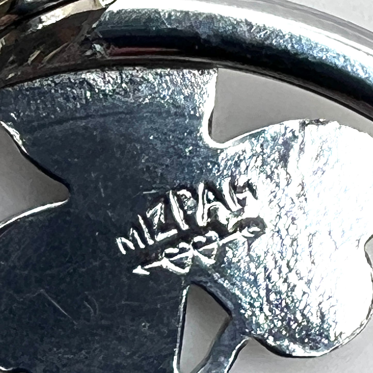 Close-up of Mizpah hallmark on vintage green enamel shamrock brooch.