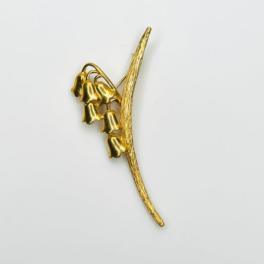 Vintage 1960s Monet gold-tone lily of the valley brooch with six bell-shaped flowers and textured curved stem
