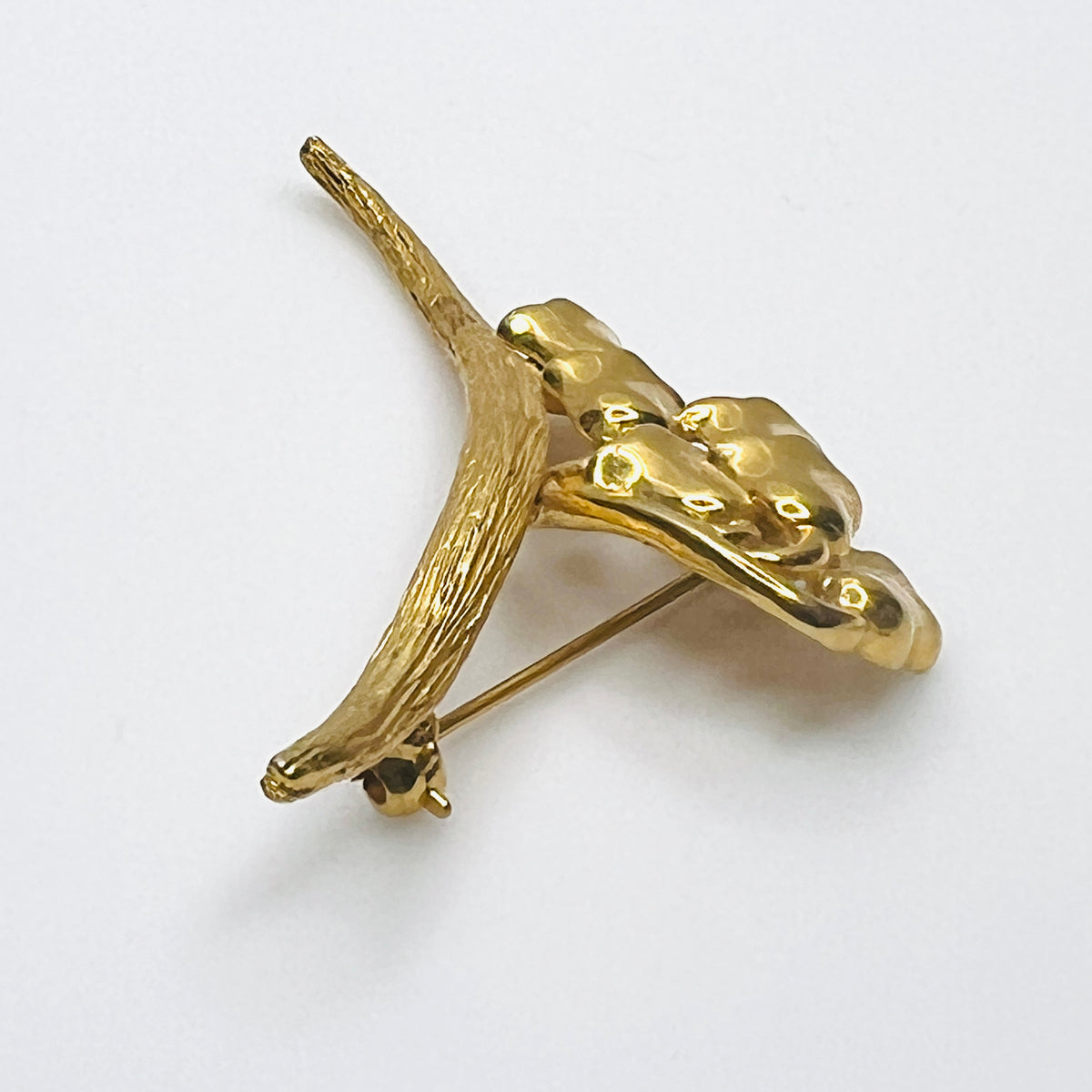 Side view of vintage gold-tone Monet flower brooch showing dimensional bell blossoms and textured stem