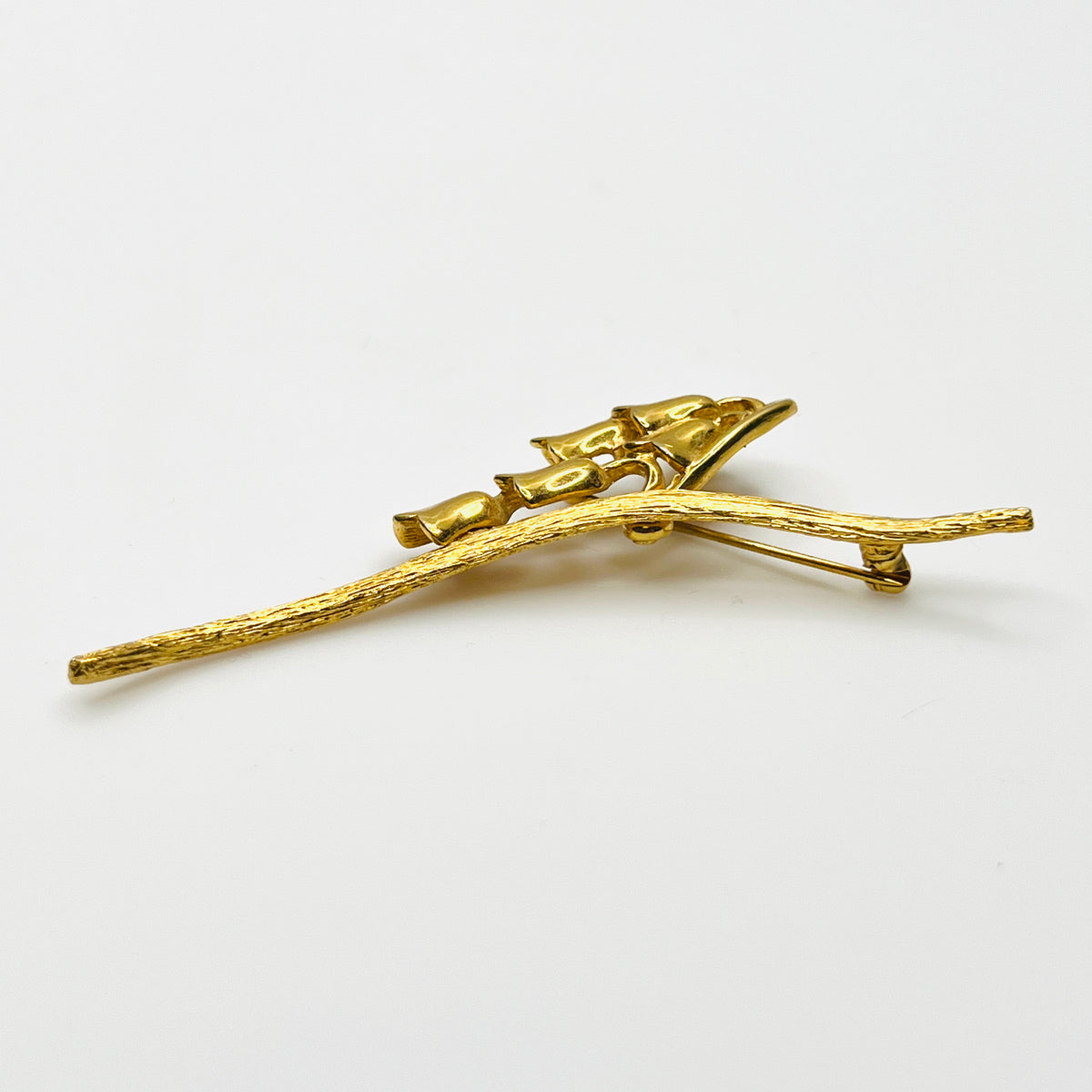 Side view of vintage gold-tone Monet flower brooch showing dimensional bell blossoms and textured stem