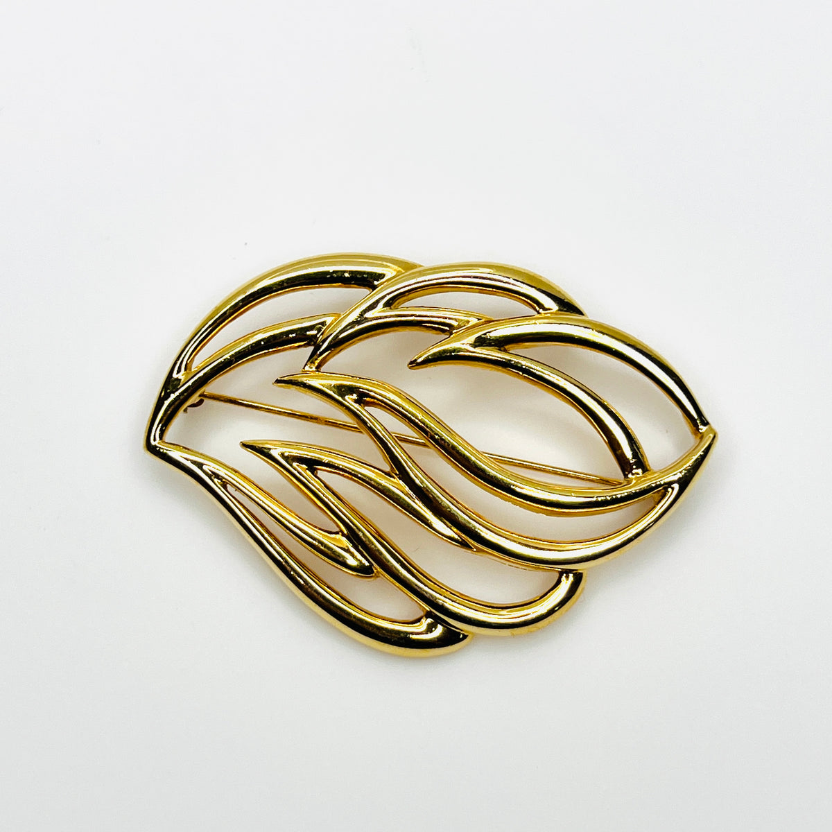 Vintage 1980s Monet gold-tone openwork statement brooch with sweeping abstract curves and polished finish