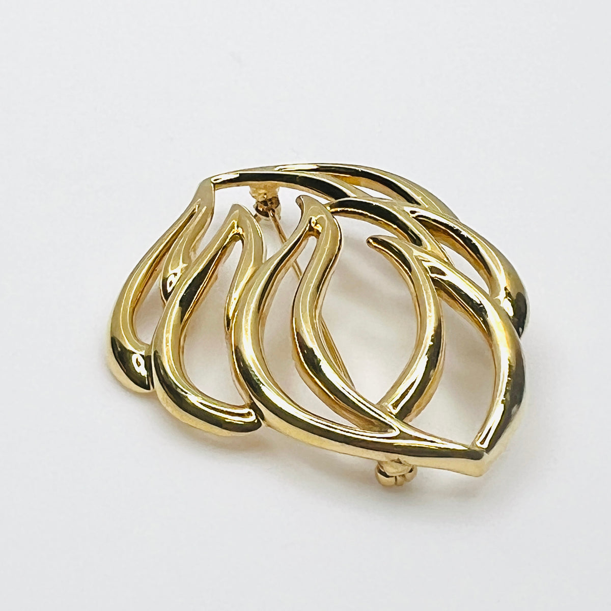 Side profile of vintage Monet statement brooch showing dimensional overlapping gold-tone metal curves