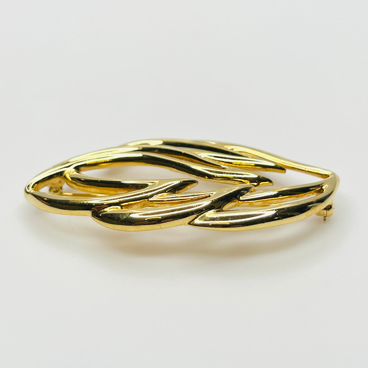Side profile of vintage Monet statement brooch showing dimensional overlapping gold-tone metal curves