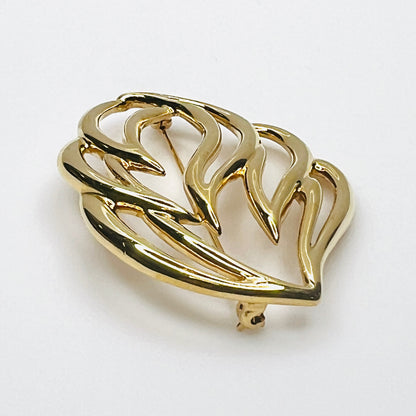 Side profile of vintage Monet statement brooch showing dimensional overlapping gold-tone metal curves