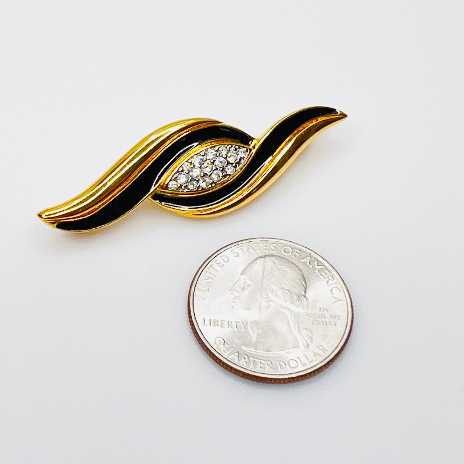 Signed Monet black enamel brooch shown beside quarter for size reference