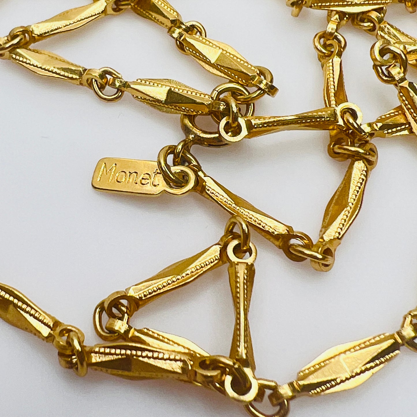 Close up of Monet hang tag and textured gold links