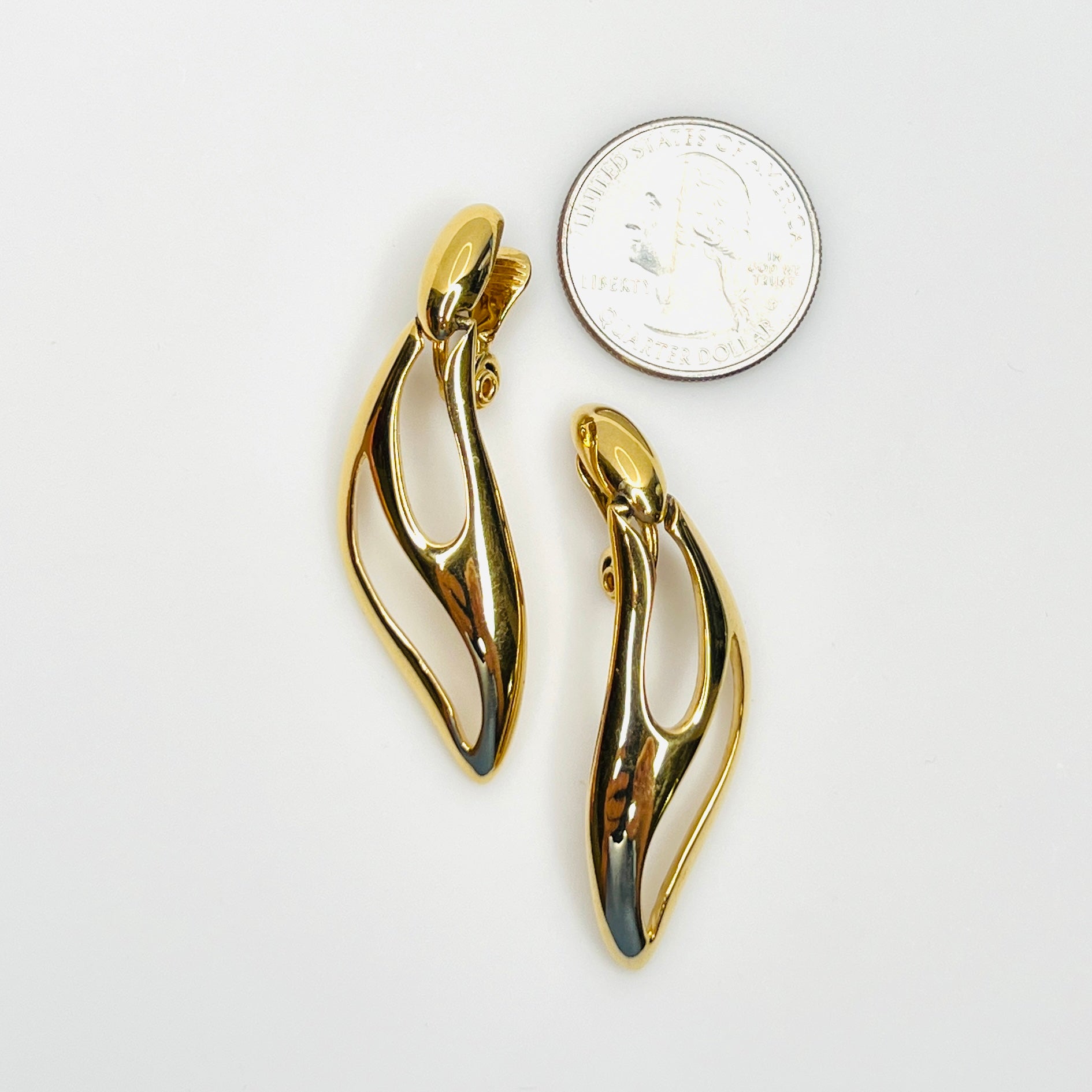 Signed Monet gold-tone modernist earrings shown beside quarter for scale