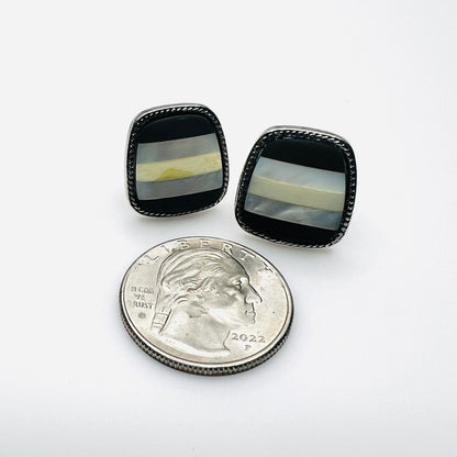 Monet onyx and mother of pearl clip earrings beside quarter for size comparison