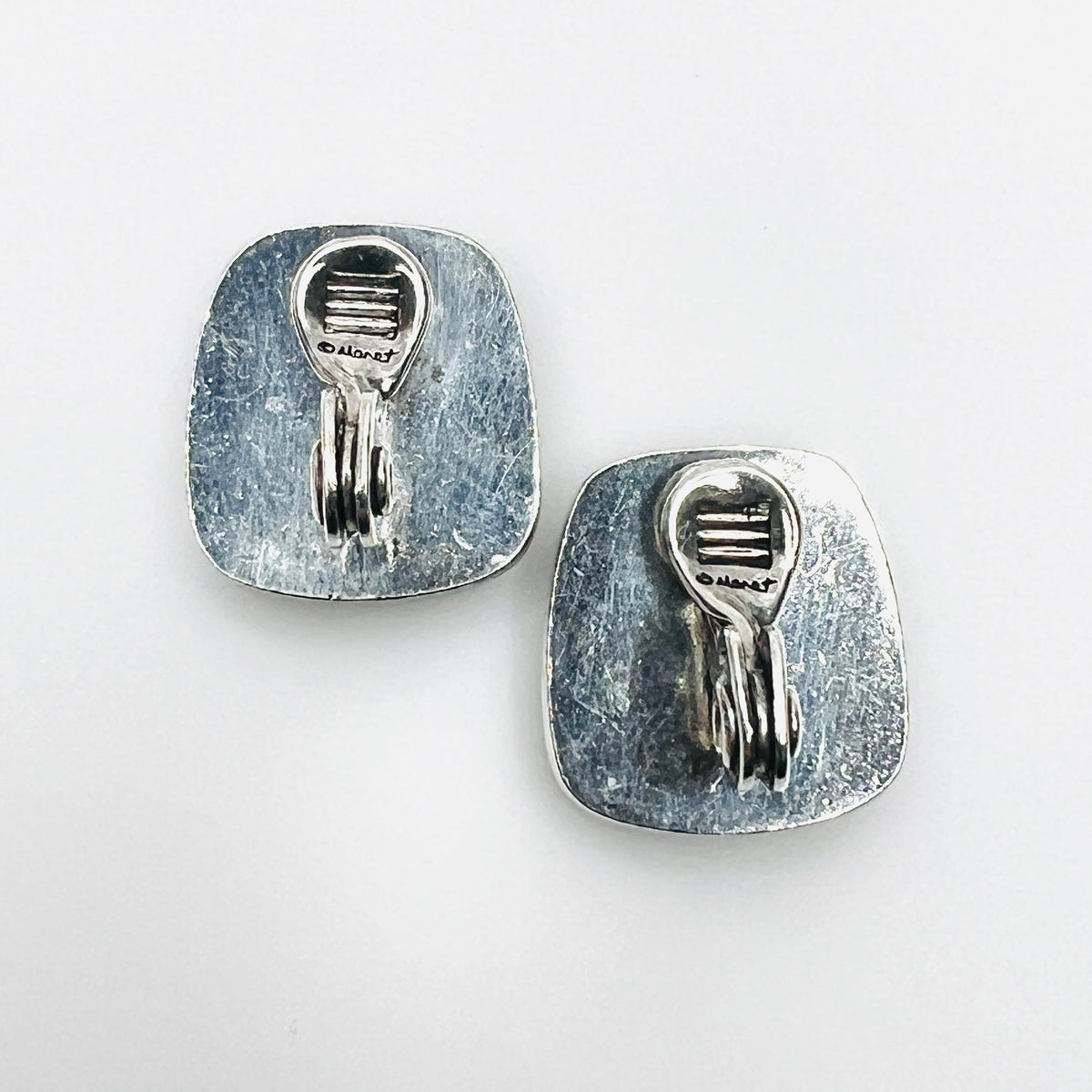 Reverse of Monet clip-on earrings showing silver-tone backs and clip fittings