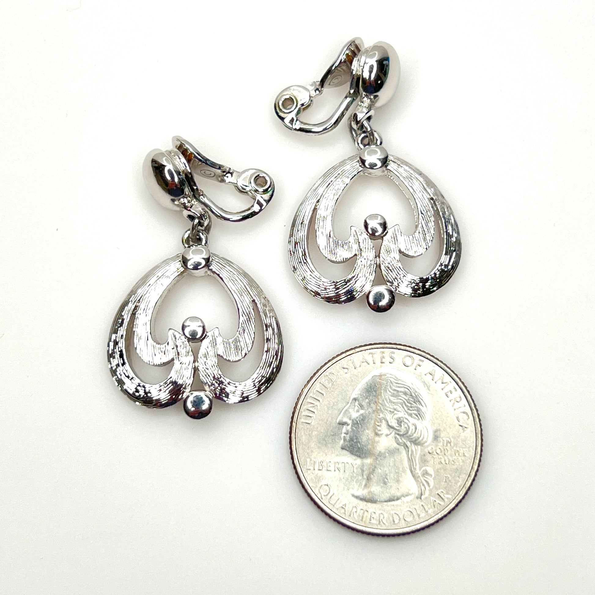 Mid-century Monet silver tone openwork dangle earrings with clip backs with quarter for scale