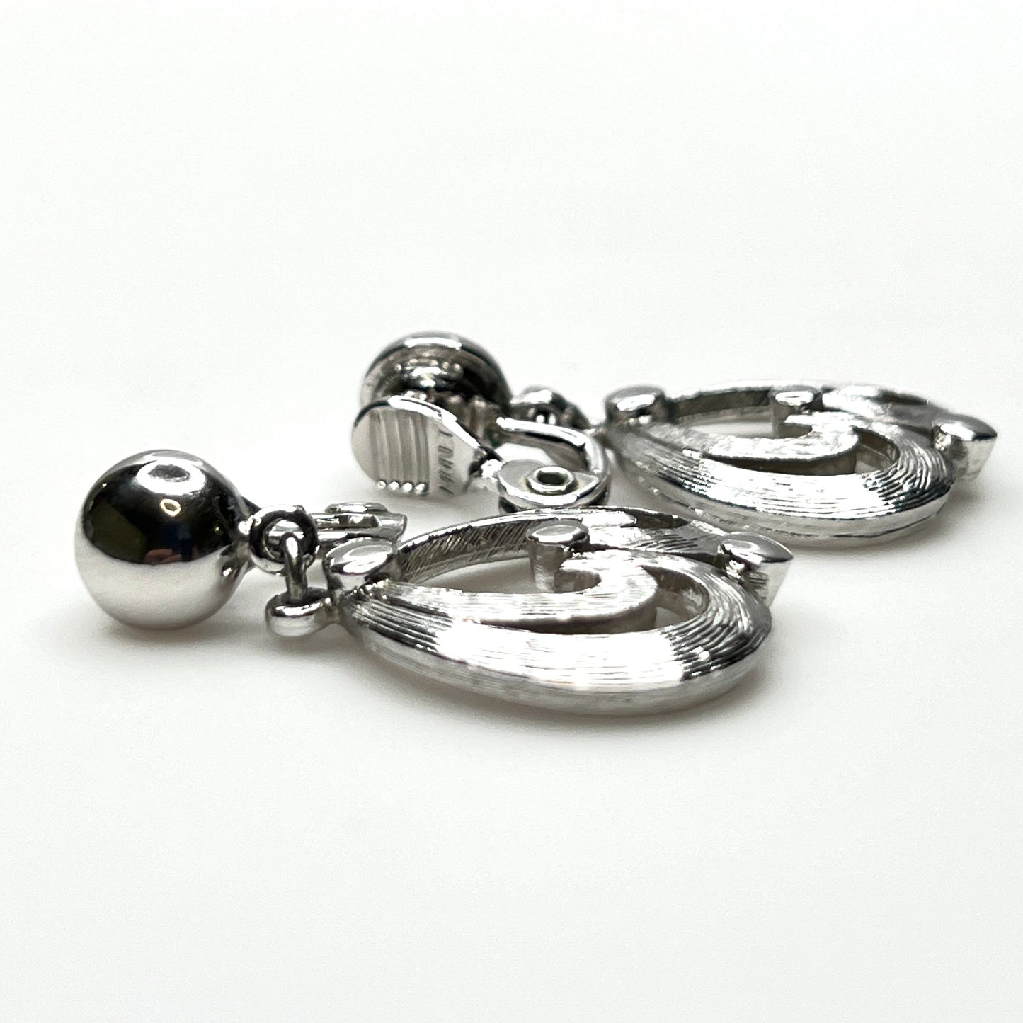 Side view of vintage Monet silver tone articulated clip-on earrings