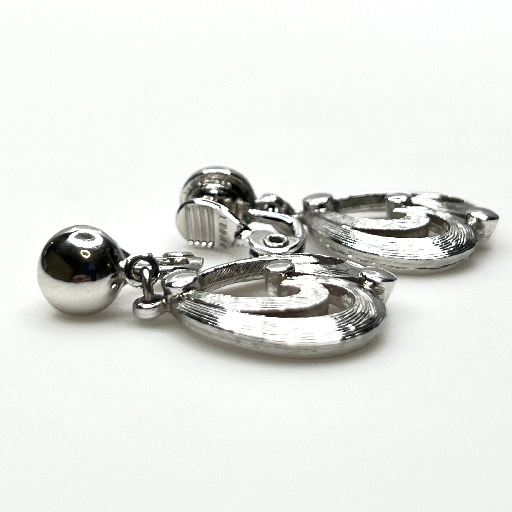 Side view of vintage Monet silver tone articulated clip-on earrings