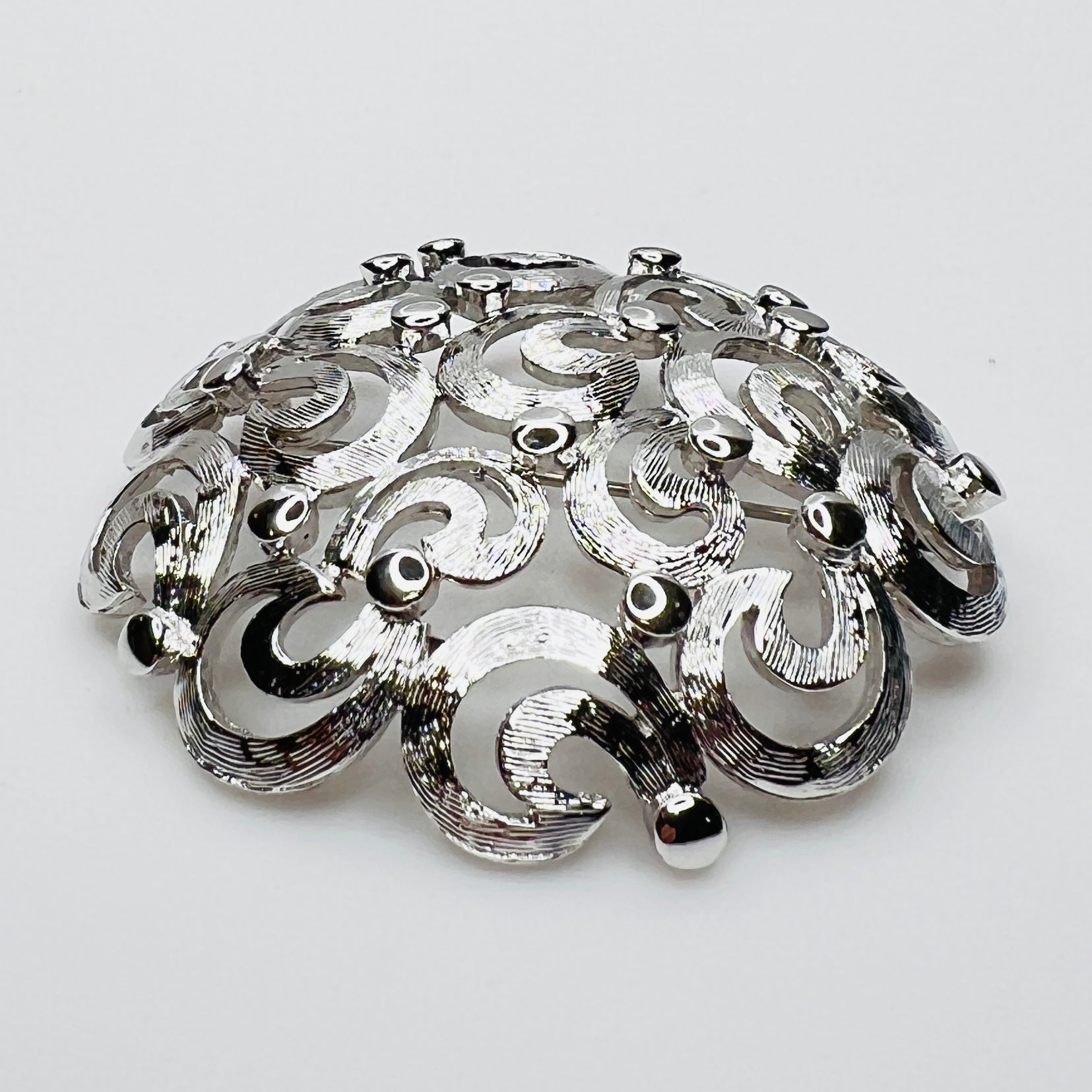 Side View of textured swirl filigree silver tone brooch