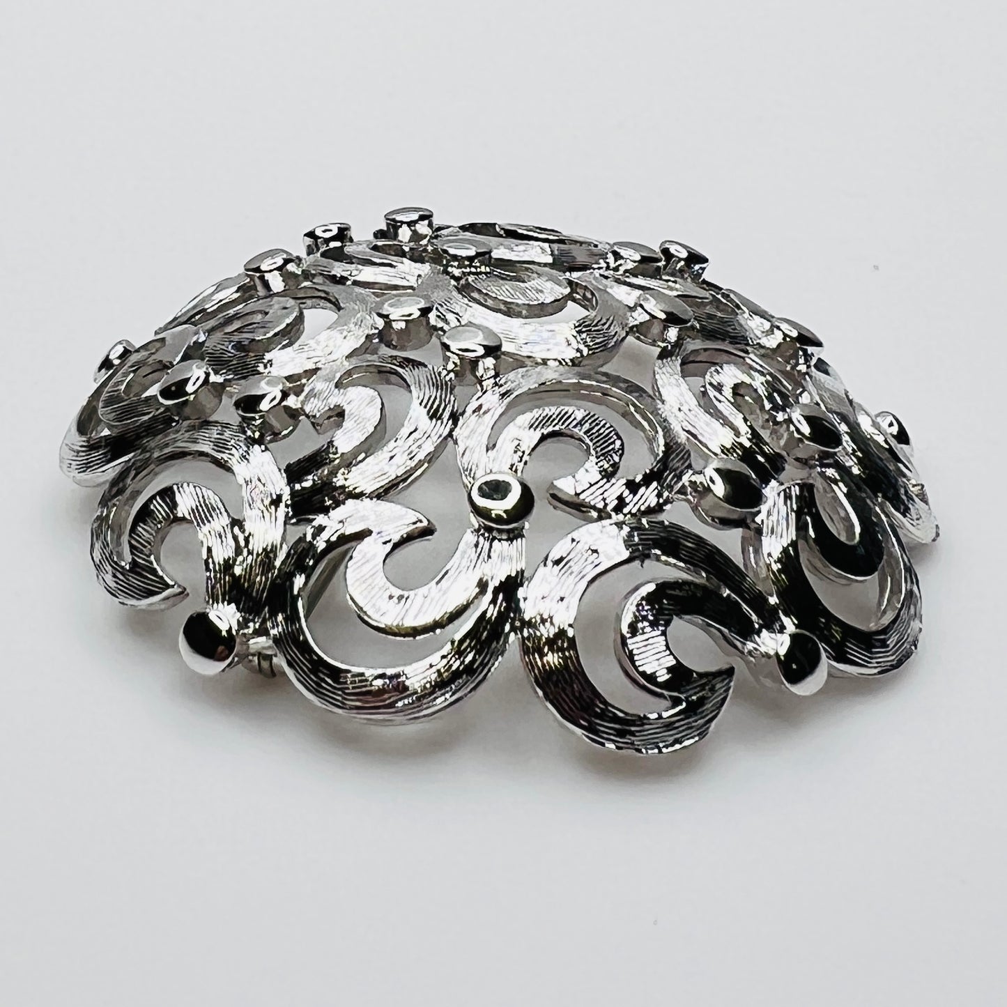 Side View of textured swirl filigree silver tone brooch