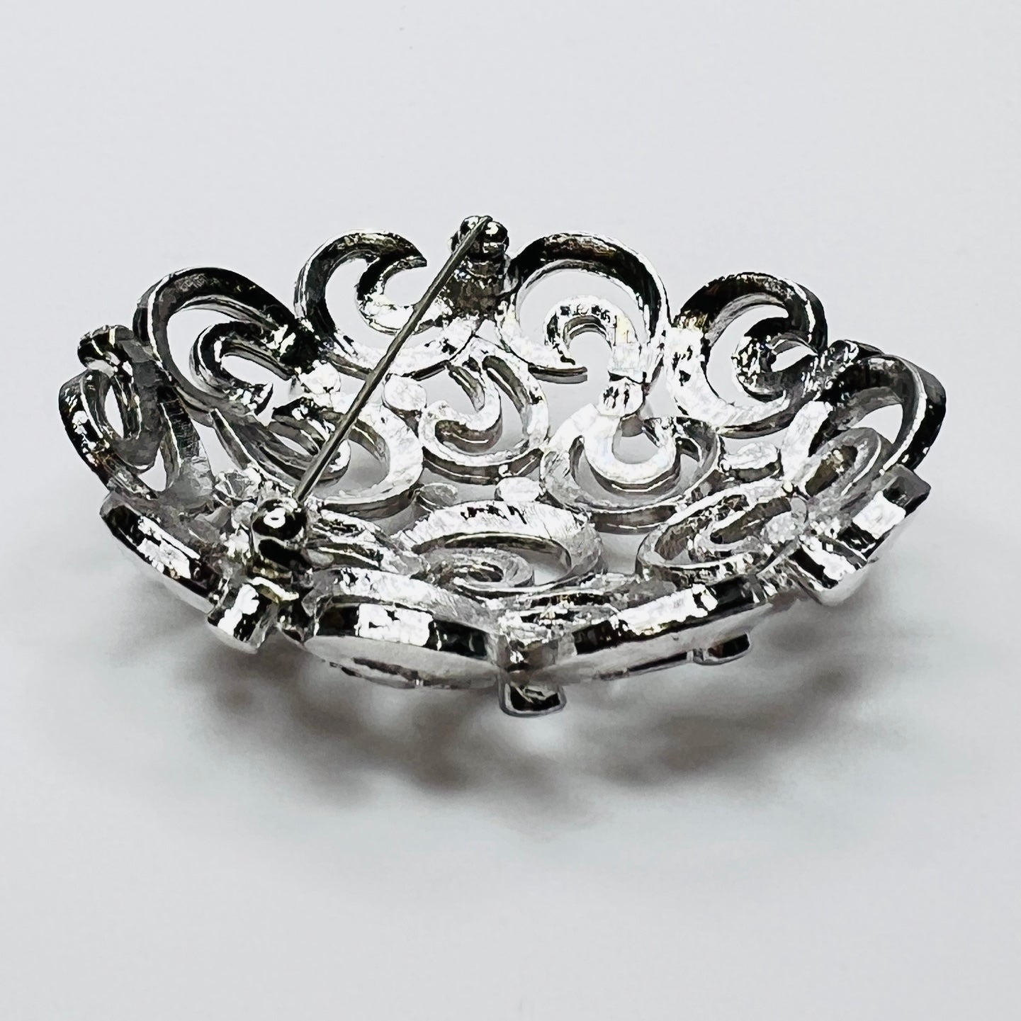 Close-up of textured swirl filigree silver tone brooch