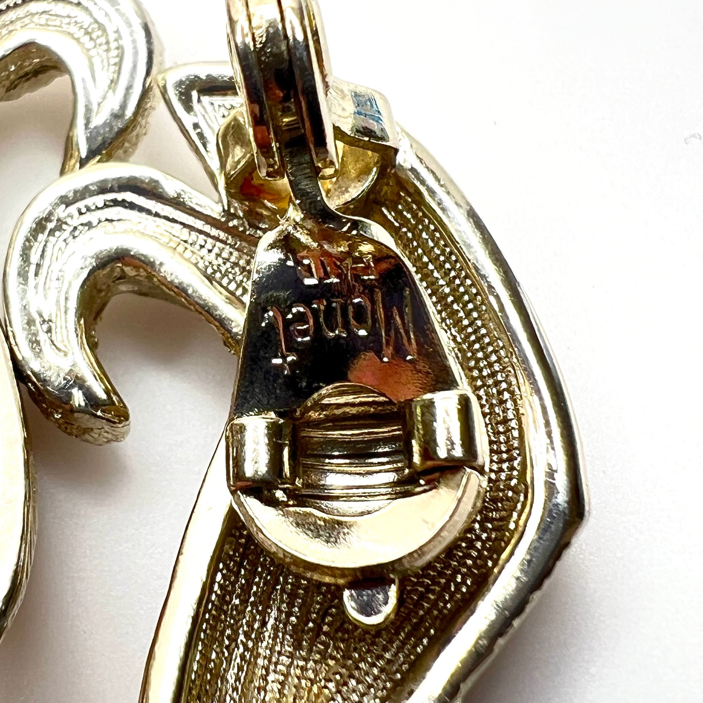 Close-up of Monet PATD. hallmark on vintage gold tone clip-on earrings