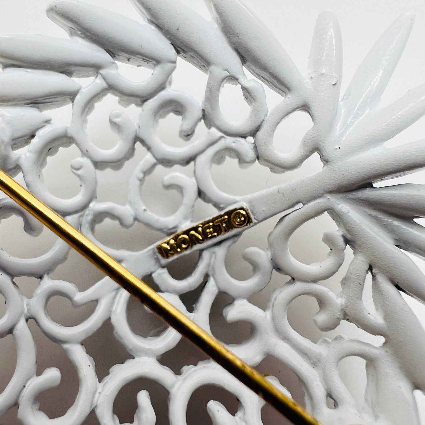 Close up of Monet signature on white enamel brooch