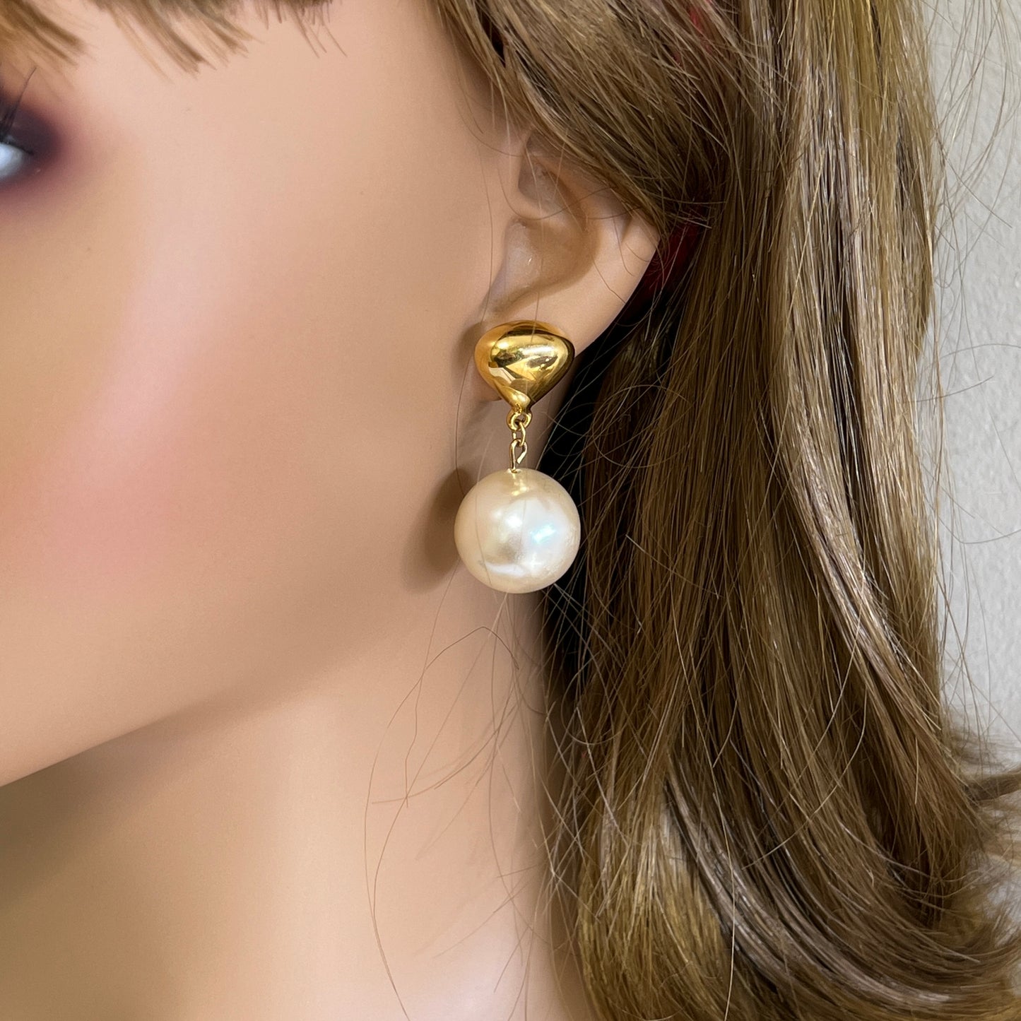 Oversized pearl dangle earrings worn on ear