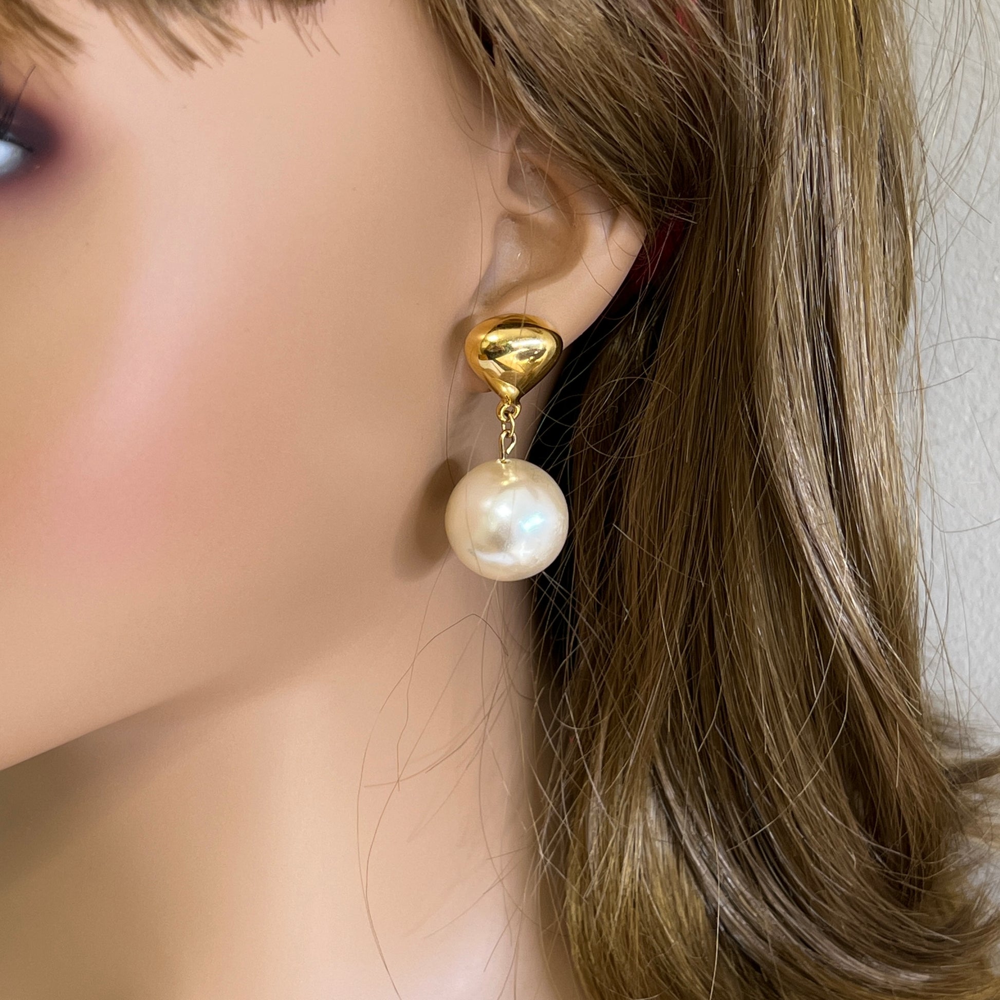Oversized pearl dangle earrings worn on ear