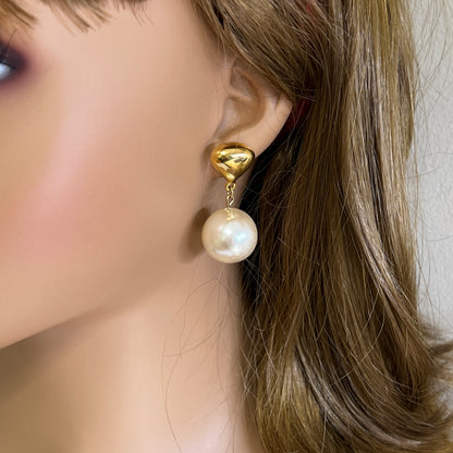 Oversized pearl dangle earrings worn on ear