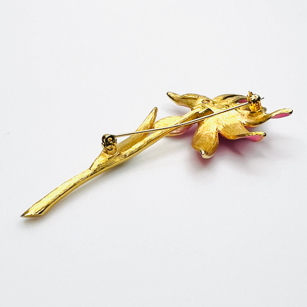 Side view of dimensional pink enamel flower brooch with layered petals and long gold stem