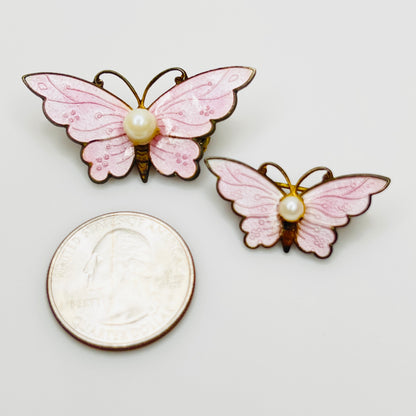 1950s pink butterfly brooch set with pearl accents shown beside quarter