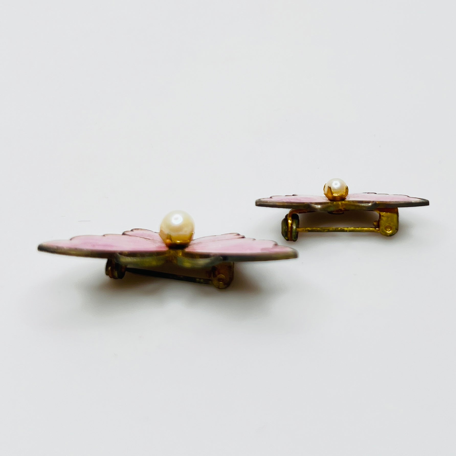 Side view of vintage butterfly brooches with pink enamel wings and pearls