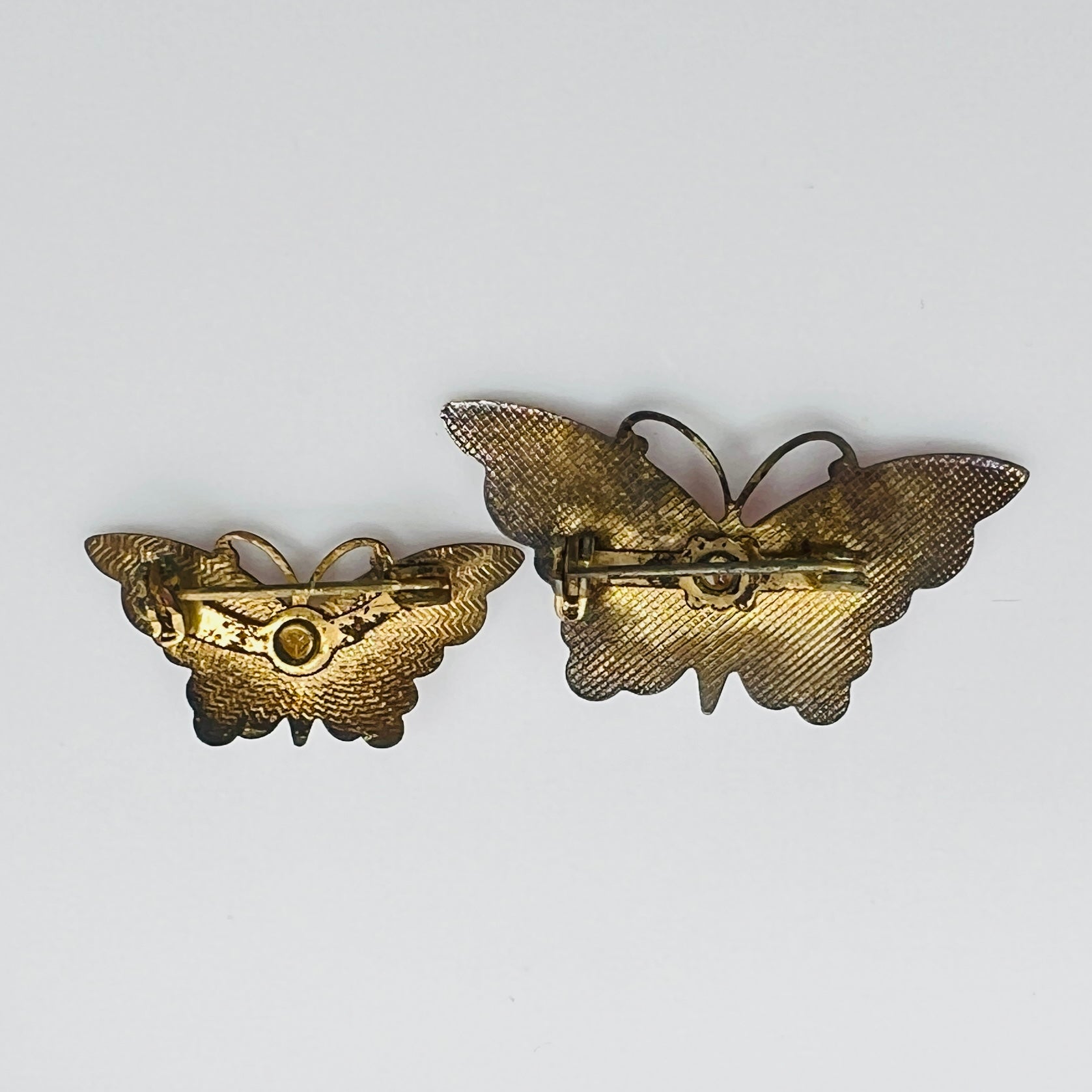 Reverse of vintage butterfly brooch pair showing clasps and aged patina