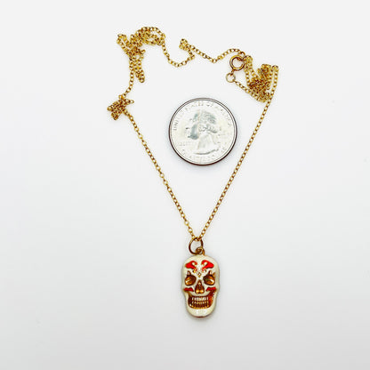 Enamel sugar skull pendant necklace beside quarter showing size and 20-inch chain.