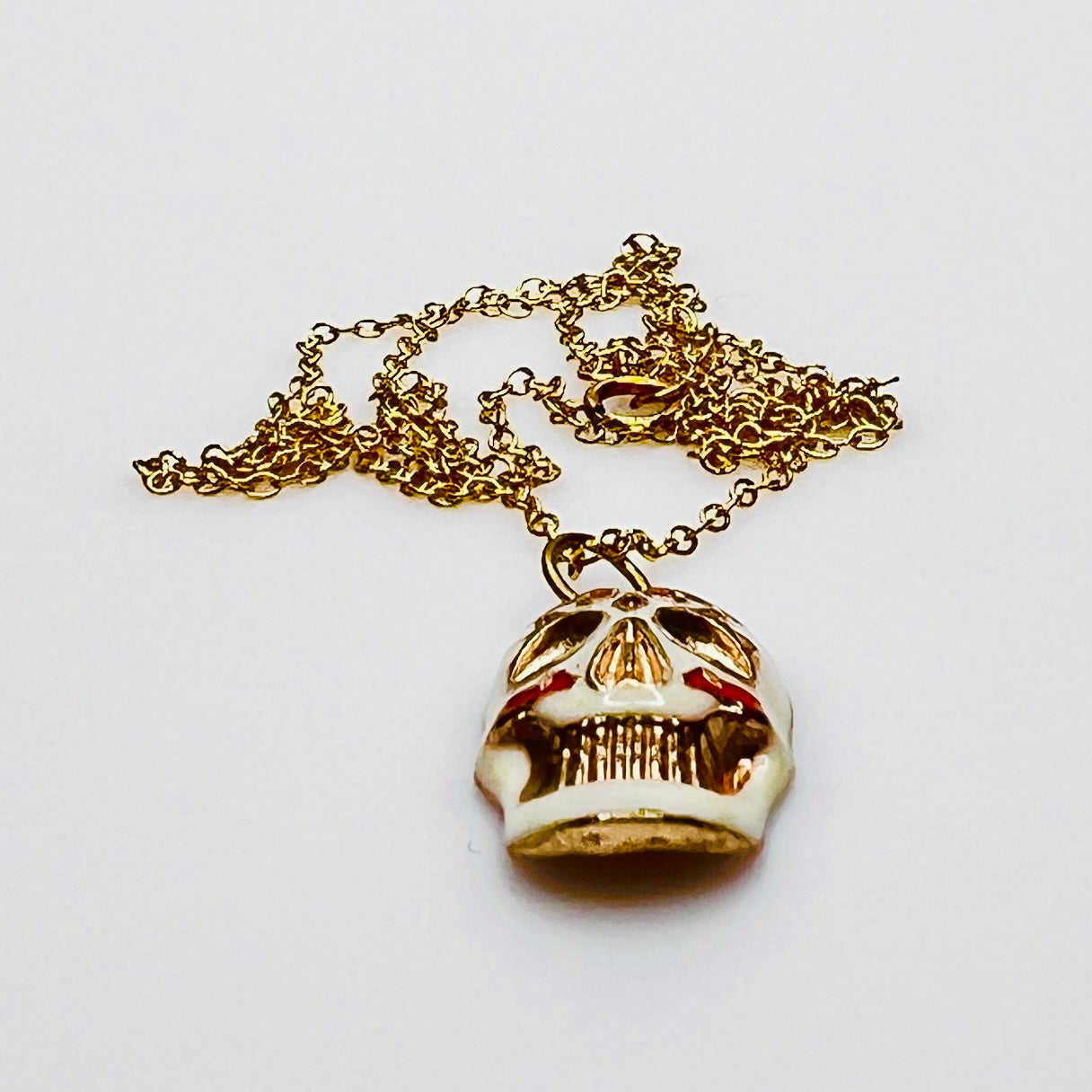 Side view of vintage enamel skull pendant with gold-filled chain.