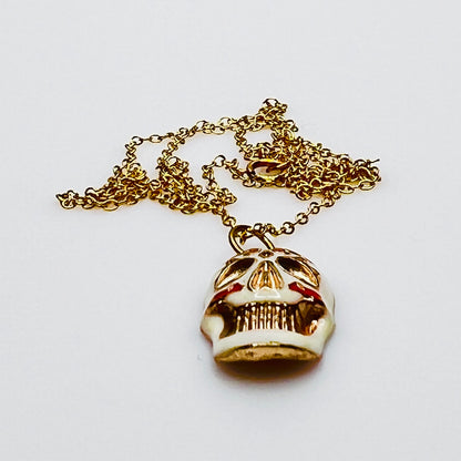 Side view of vintage enamel skull pendant with gold-filled chain.