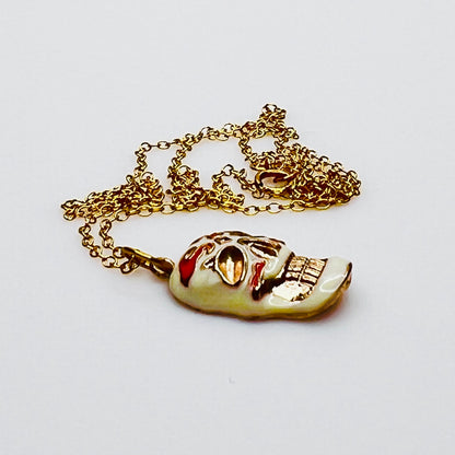 Side view of vintage enamel skull pendant with gold-filled chain.