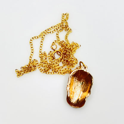 Back of enamel sugar skull pendant showing polished gold-tone finish.