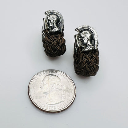 Roman soldier cufflinks with braided brown wrap next to coin