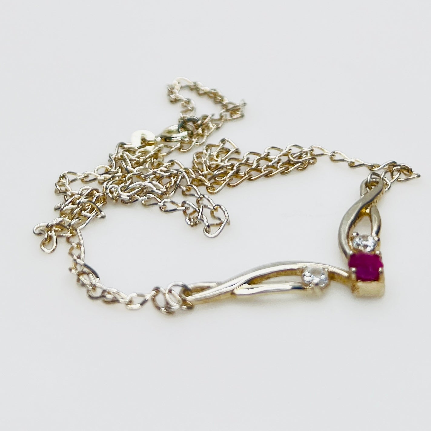 Close view of silver swirl pendant with ruby and CZ stones