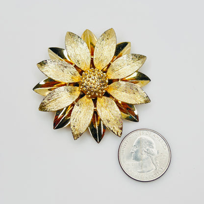 Gold floral brooch beside quarter for scale