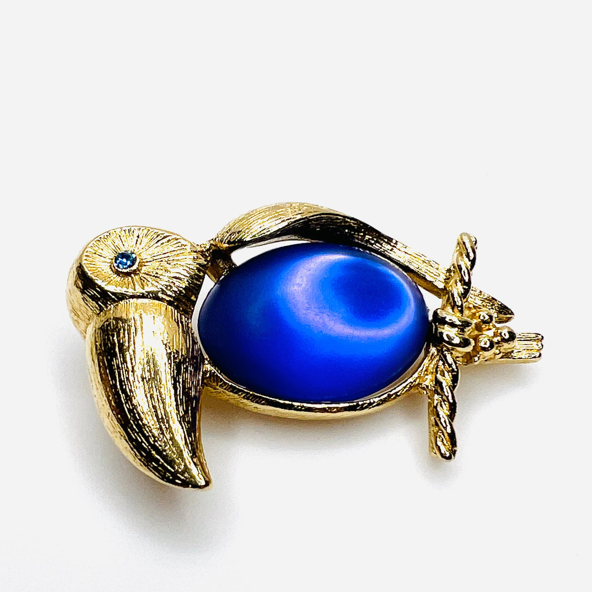 side view of gold-tone toucan brooch with luminous purple cabochon belly and rhinestone eye