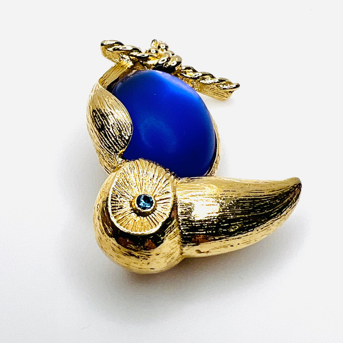side view of gold-tone toucan brooch with luminous purple cabochon belly and rhinestone eye