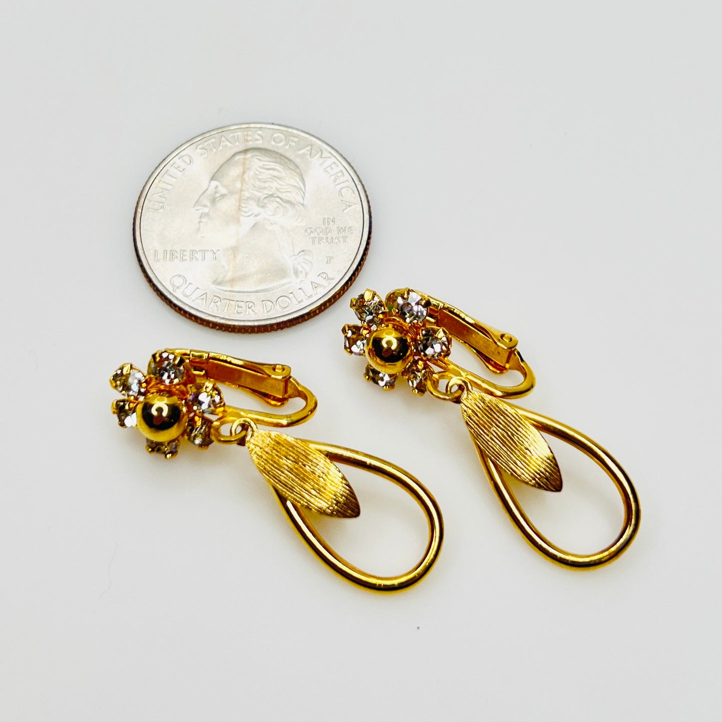 Signed Sarah Coventry 1960s clip earrings beside quarter for size comparison