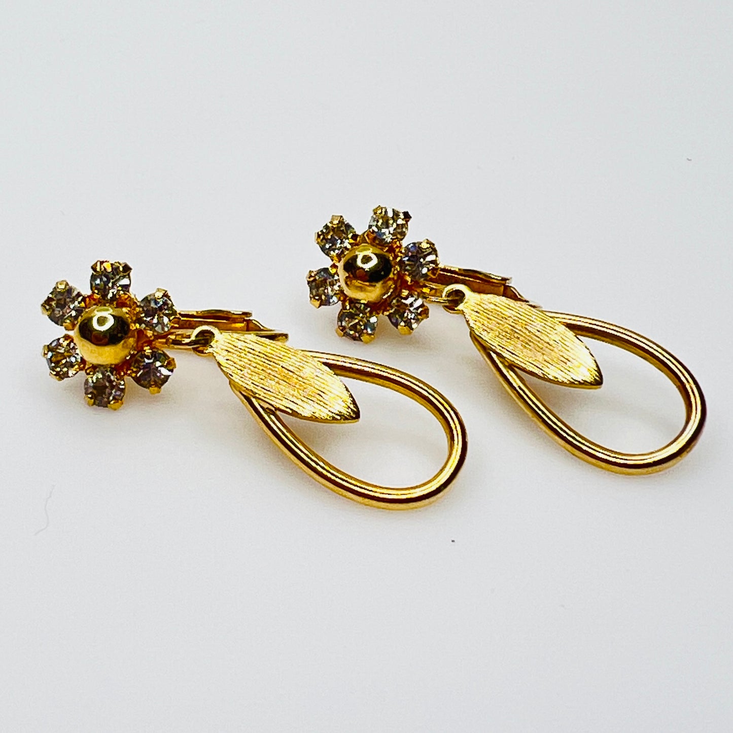 Gold tone rhinestone dangle clip on earrings with open teardrop design