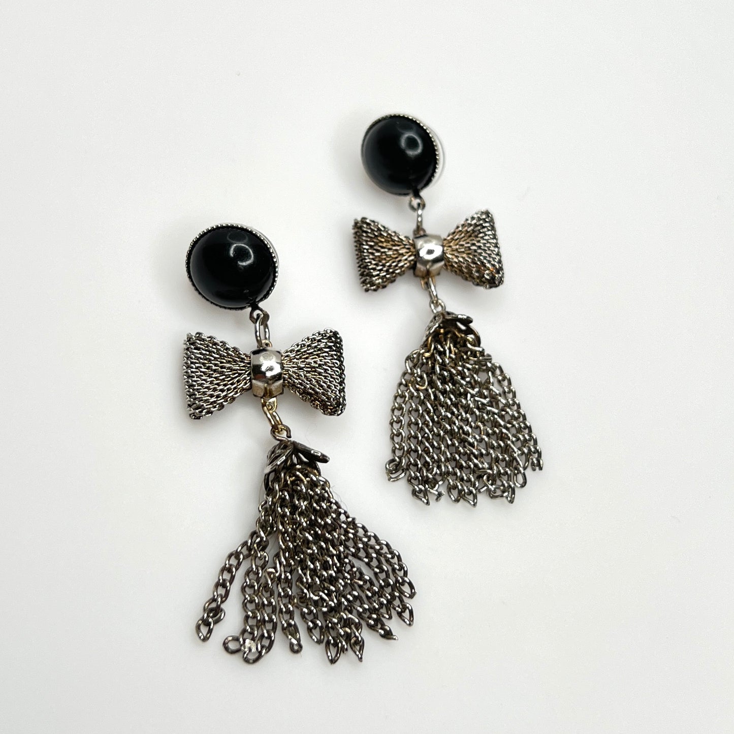 Vintage 1970s silver tone mesh bow earrings with chain tassel dangles and black acrylic studs