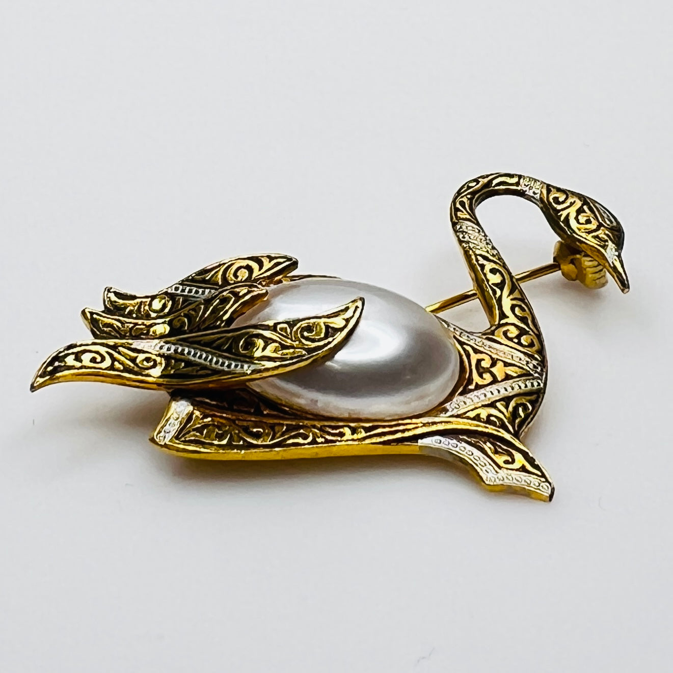Side view of vintage swan brooch with faux pearl cabochon center